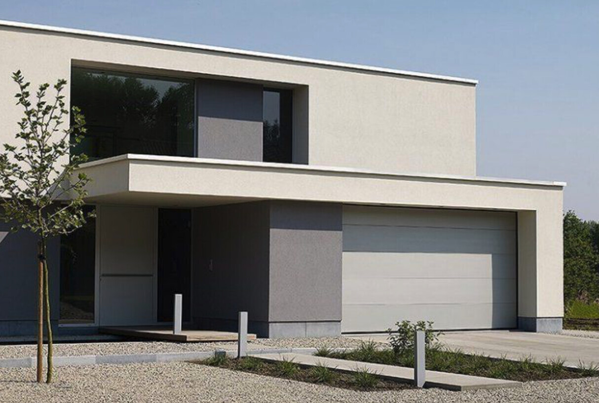 Moderne weiße Villa mit Flachdach, großer Garage, Zugangspfad und Kiesgarten.