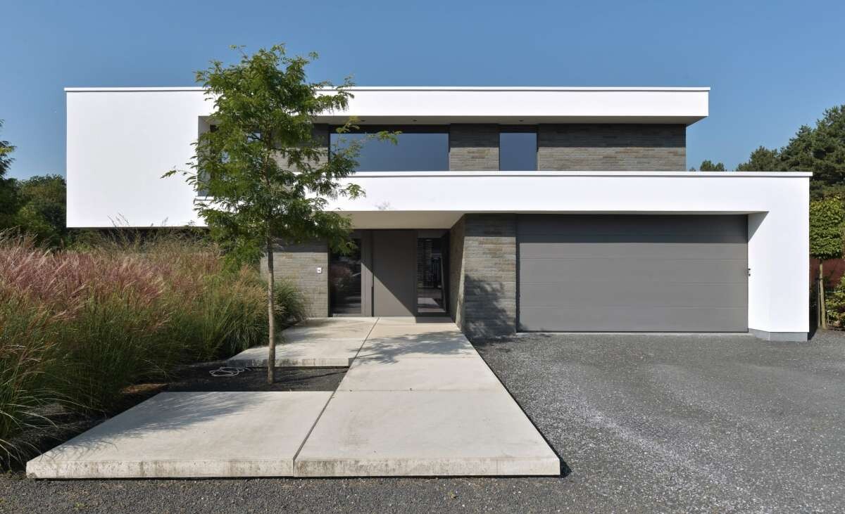 Moderne weiße Hausfront mit grauer Doppelgarage, Eingang und Gartenweg