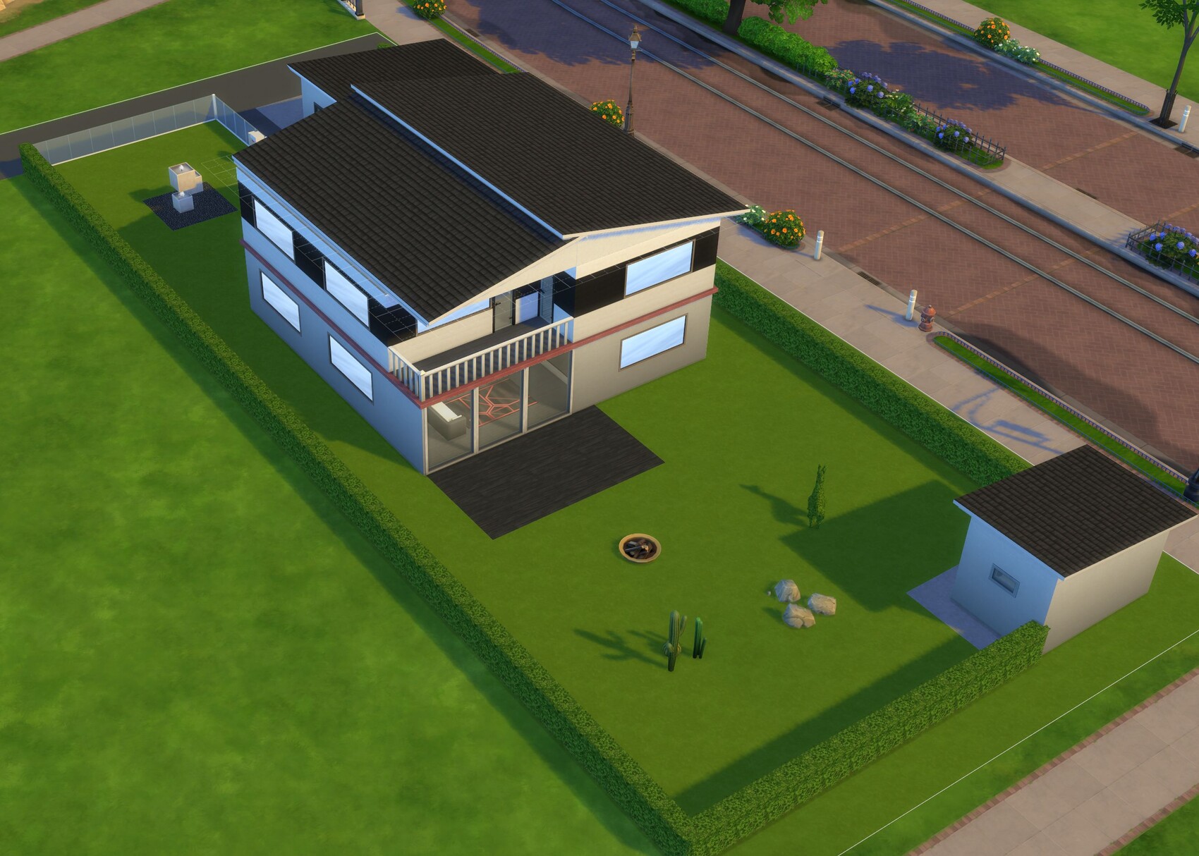 Aerial view of a modern two-story house with green lawn, hedge and patio.