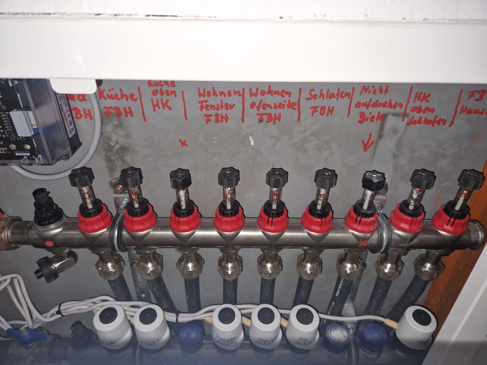 Verteilersystem mit Rohren und roten Absperrventilen in Haustechnikinstallation