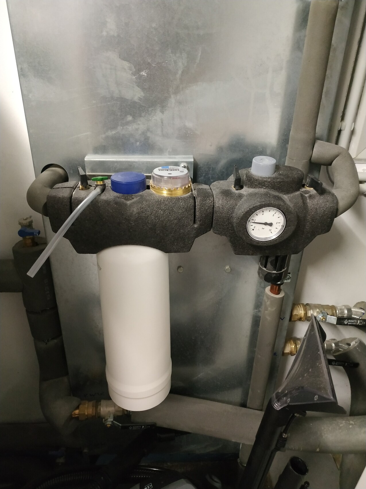 Wasserfilteranlage mit Druckmesser, schaumisolierten Ventilen und weißer Filterkartusche.