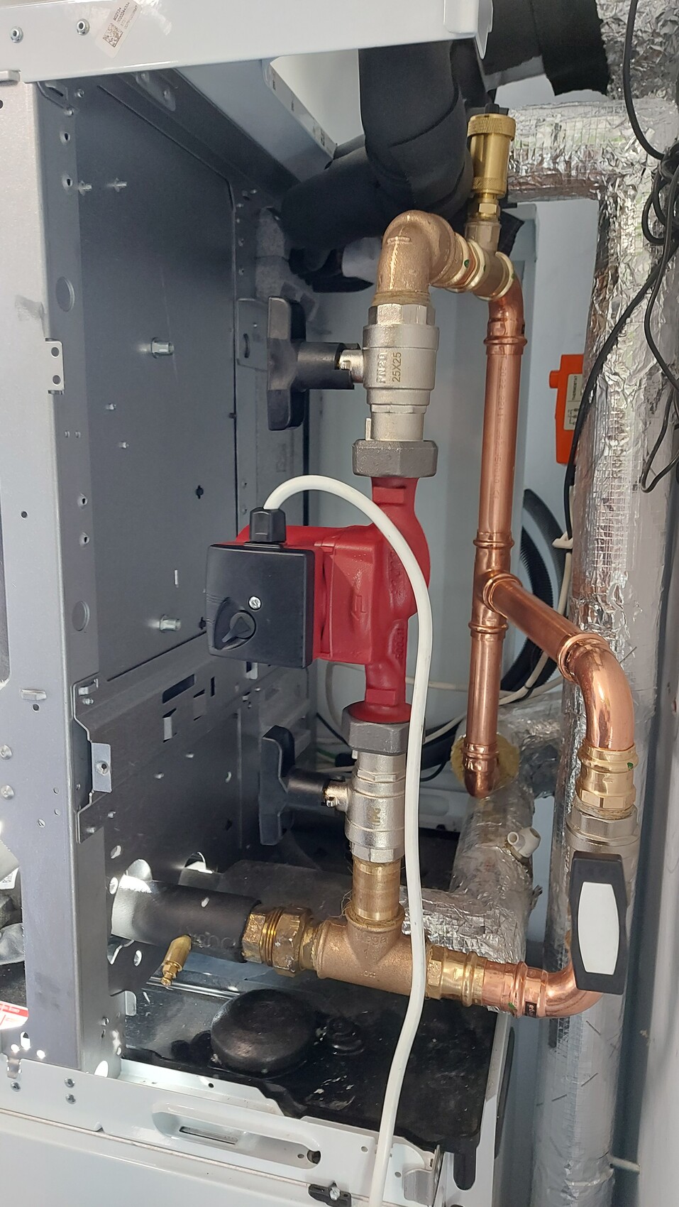 Heizungsanlage mit Kupferrohren, roter Pumpe, Absperrventil und Isolierung.