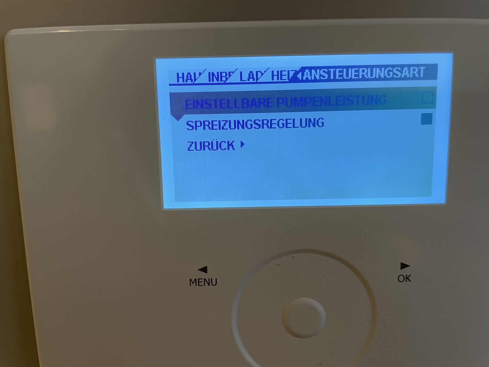 Blau beleuchtetes Heizungsbedienpanel mit Bildschirmtext: Einstellungen, Zurück, Spreizungsregelung.
