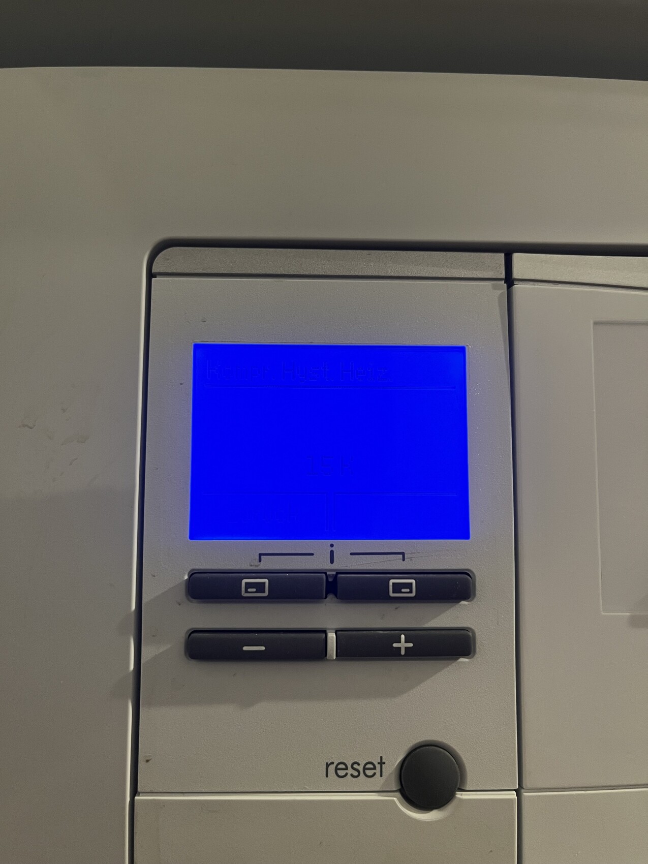 Digitaler Heizungsregler mit blau beleuchtetem Display, Tastenfeld und Reset-Knopf.