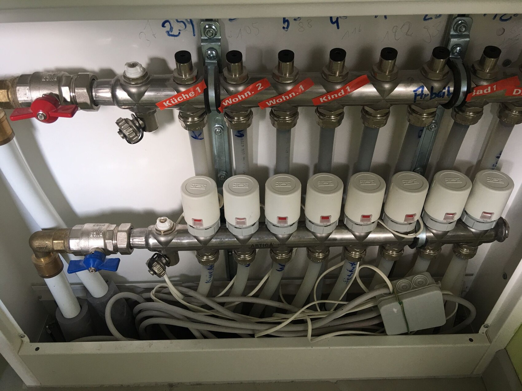 Heizungsverteiler mit Absperrventilen und Thermostatköpfen; Etiketten Küche 1, Wohn 2, Kind 1