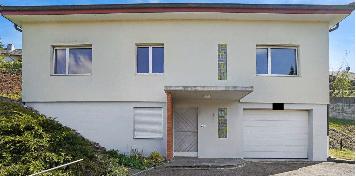 Zweistöckiges Haus mit Garage, weiße Fassade, Eingang unter Vordach.