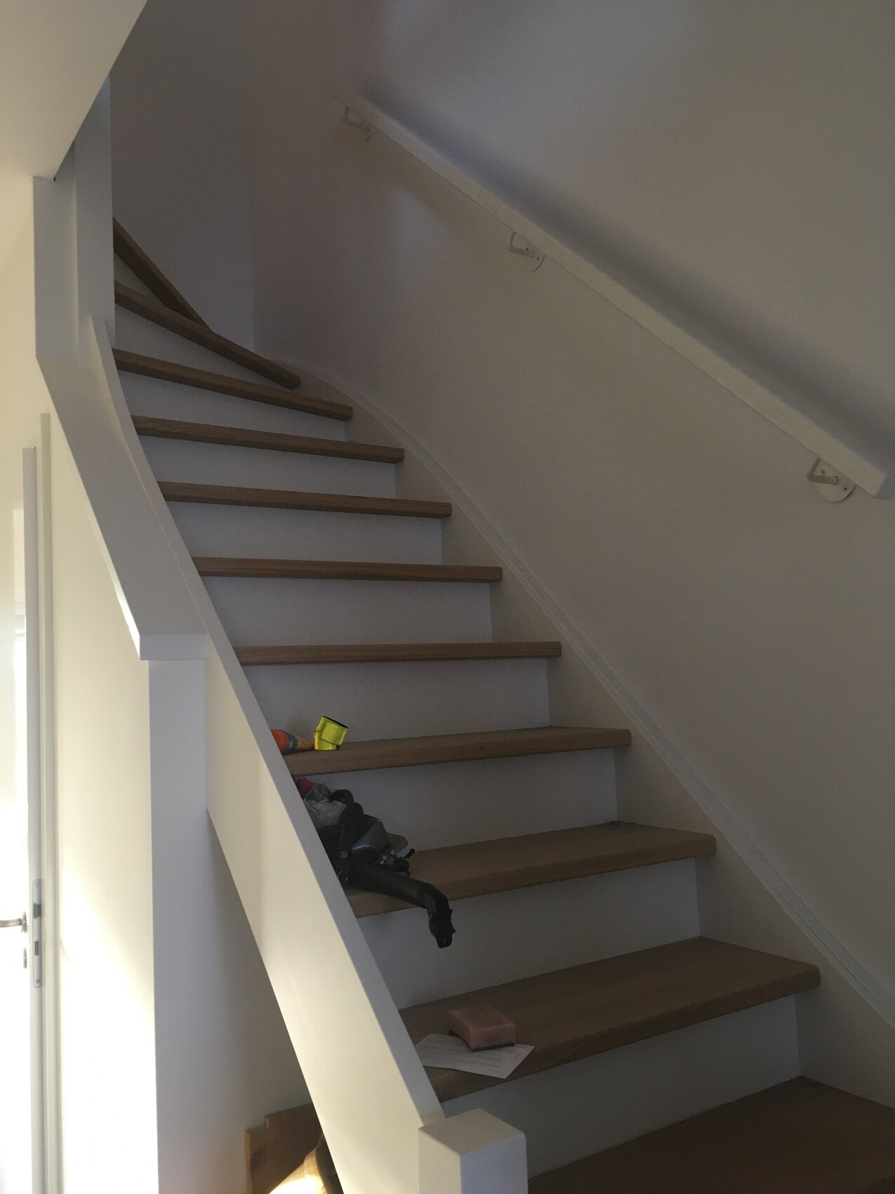 Innenraum: Holztreppe mit weißem Geländer, Gegenstände auf den Stufen.