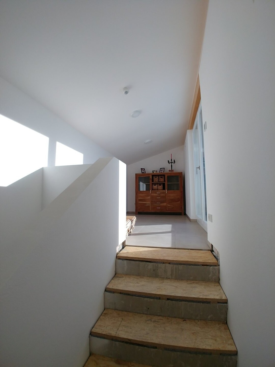 Moderne helle Treppe im Flur mit weißen Wänden und Holzstufen
