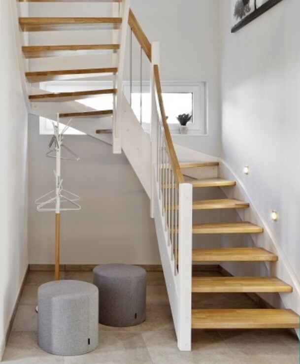 Moderne helle Treppe mit Holztreppenstufen und weißem Geländer im Flur, Kleiderständer und Hocker