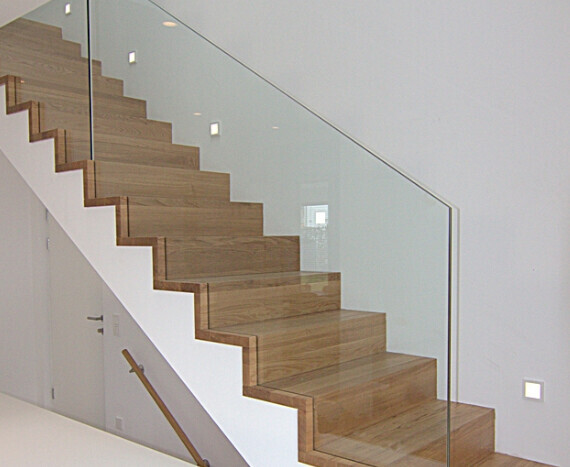 Moderne Holztreppe mit Glasgeländer in hellem Innenraum