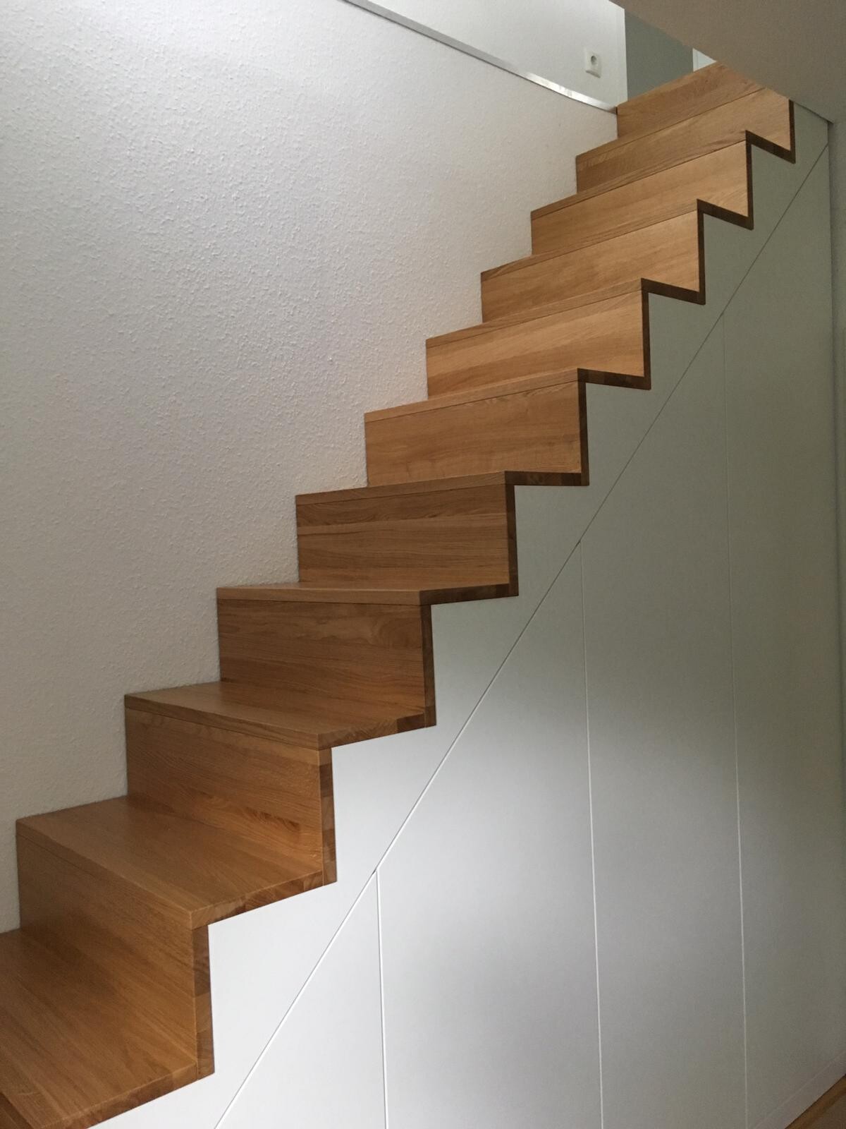 Moderne Holztreppe mit sichtbaren Holzstufen in Innenraum, weiße Wände