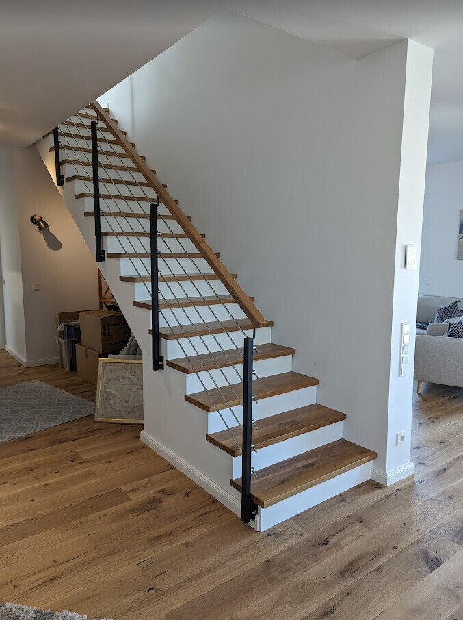 Moderne Treppe mit Holzstufen und Seilgeländer im hellen Wohnbereich