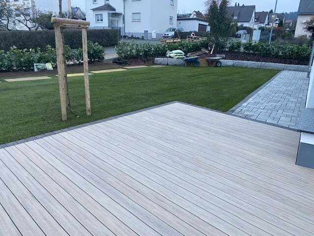 moderne-holzterrasse-im-garten-mit-gruenem-rasen-und-pflasterbereich.jpg
