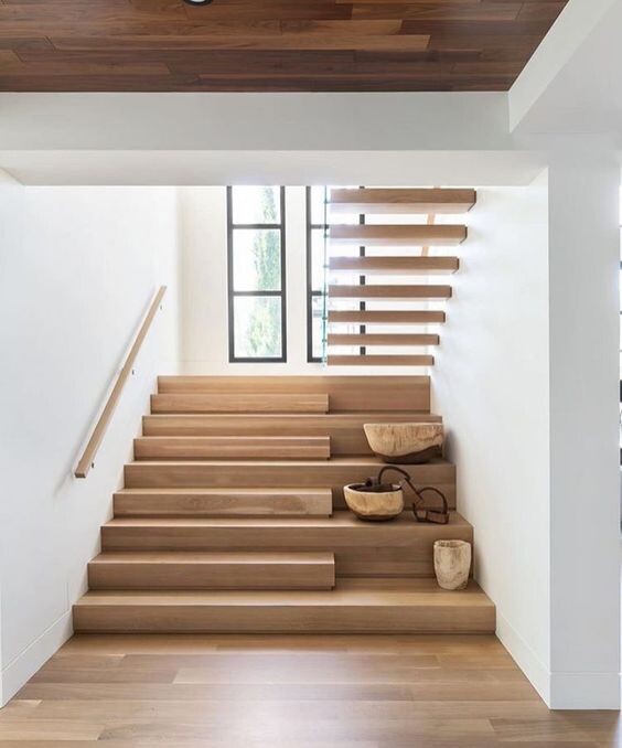 Moderne Holztreppe mit offenen Stufen in hellem Innenraum, Fenster im Hintergrund