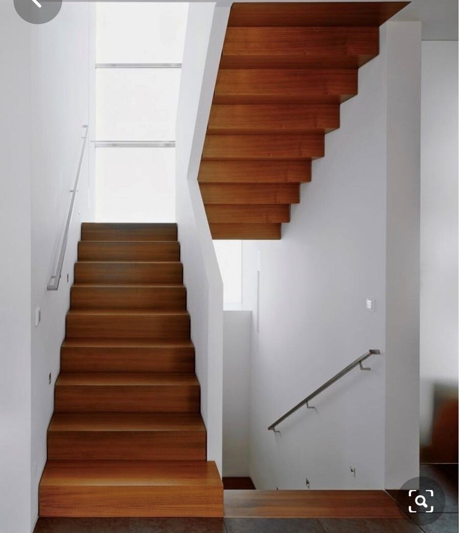 Moderne Innentreppe aus dunklem Holz, L-förmige Treppe mit zwei Abschnitten und weißen Wänden.