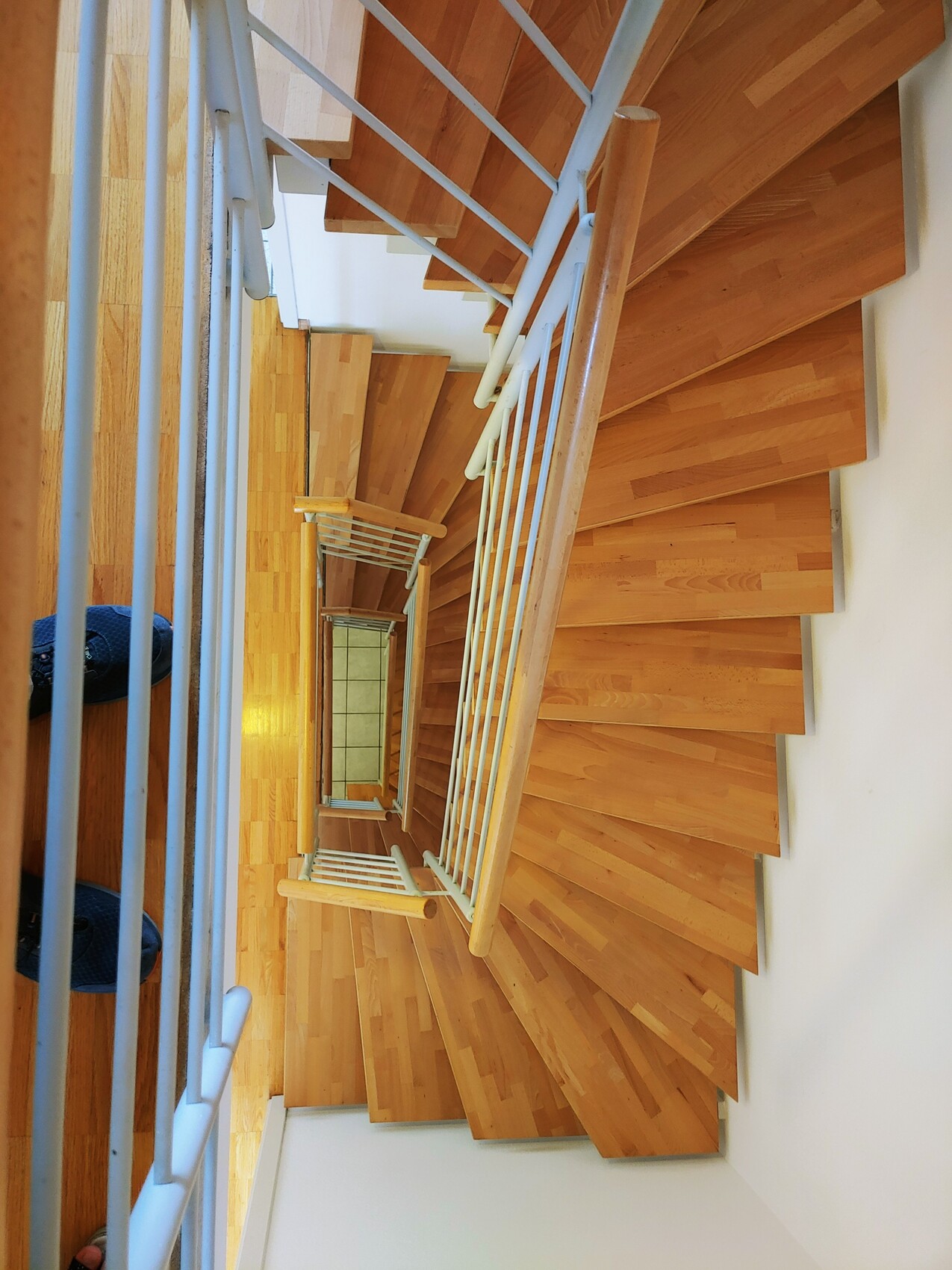 Blick von oben auf eine mehrstufige Holztreppe mit weißem Geländer.