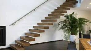 Moderne Holztreppe mit offenen Stufen und Handlauf an weißer Wand, Pflanze daneben.