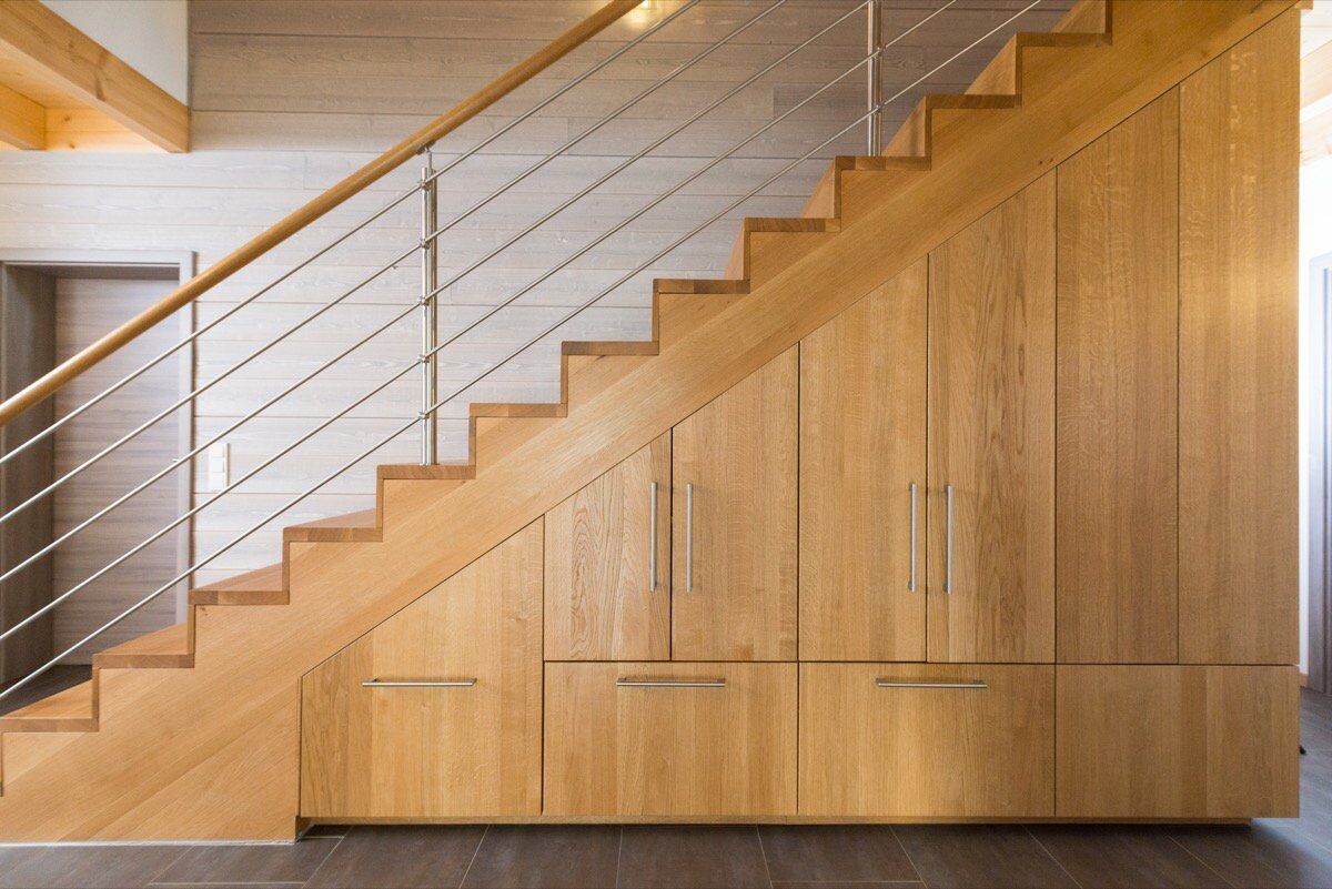 Moderne Holztreppe mit integrierten Schränken darunter und Kabelgeländer.