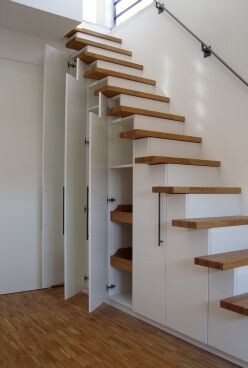Moderne Holztreppe mit offenen Stufen, integrierter Stauraum unter Treppe in weißem Innenbereich