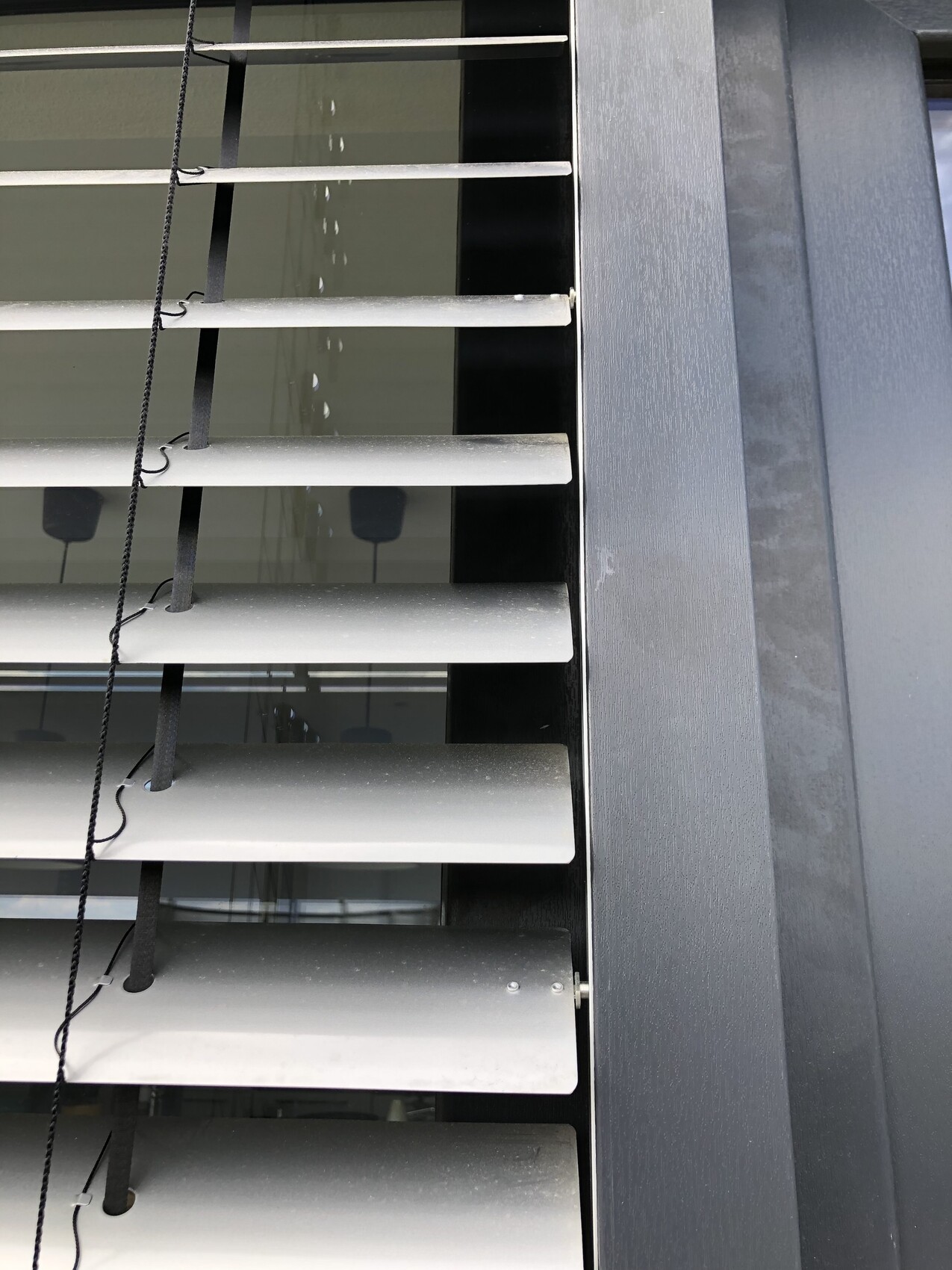 Moderne horizontale Fensterrolllaeden mit Schnur an dunkler Fassadenverkleidung