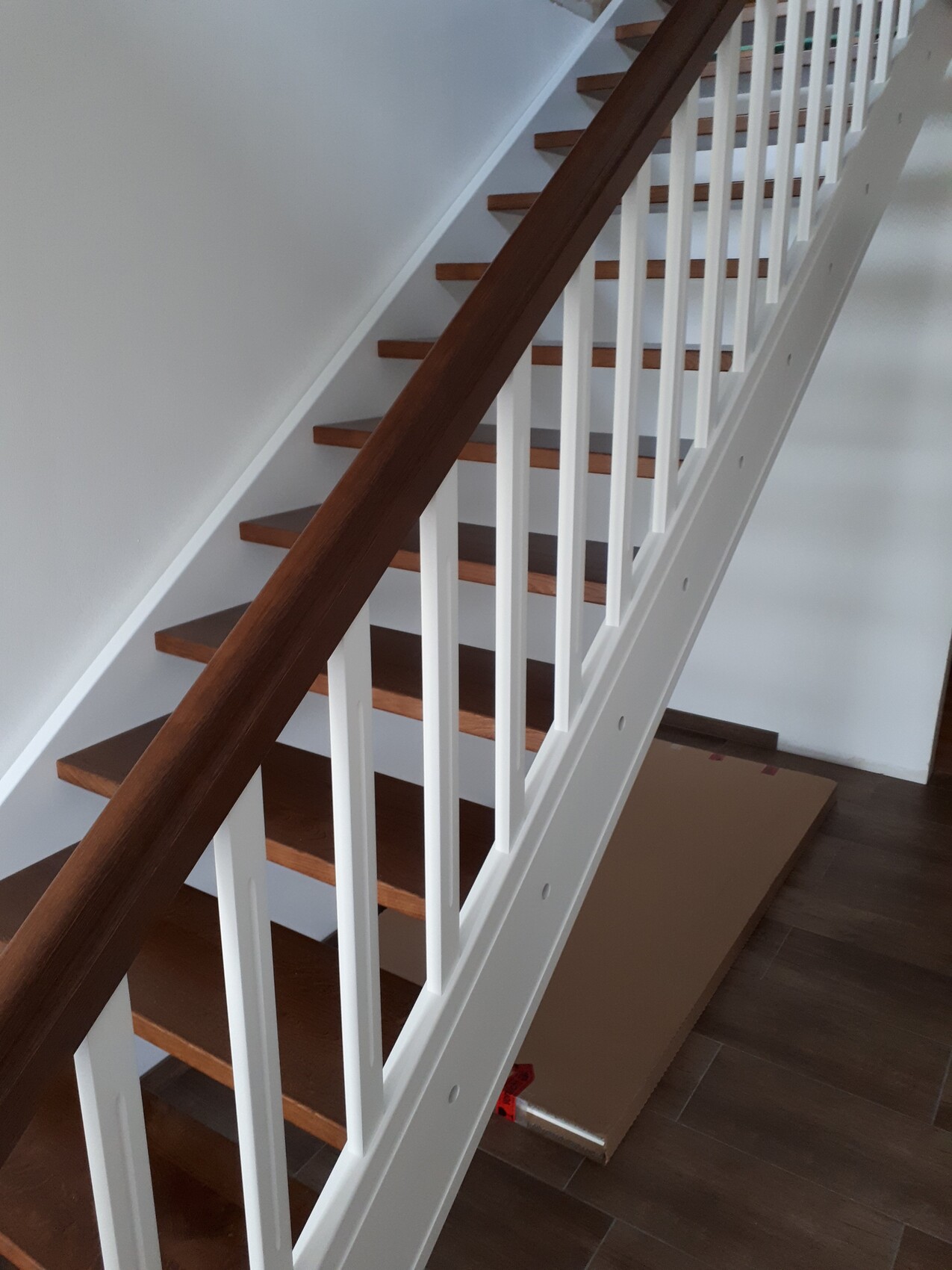 Moderne Innenholztreppe mit dunklem Holzhandlauf und weißen Geländern in einem Haus