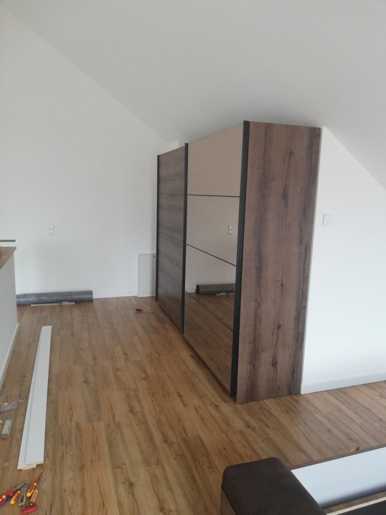 Großer Holzschrank mit Spiegel-Schiebetüren in renoviertem Zimmer.