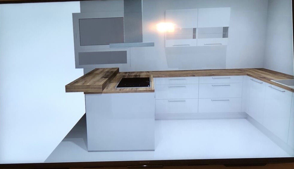 Moderne Küche mit weißen Schränken, Holz-Arbeitsplatte und Insel mit Kochfeld.