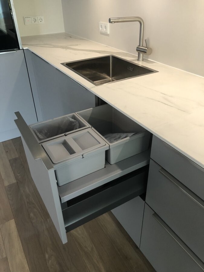 Moderne Küche mit hellgrauen Schränken, Marmoreffekt-Arbeitsplatte und Spüle