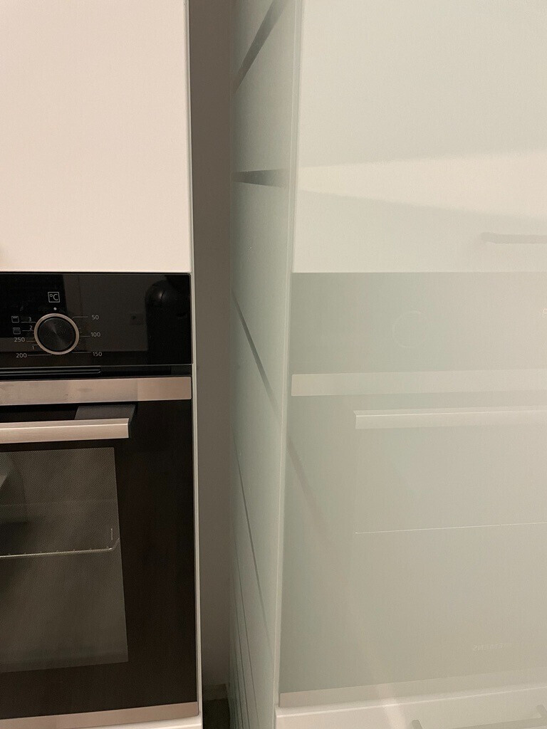 Eingebauter Backofen in moderner Küche neben weißen Hochglanz-Schränken