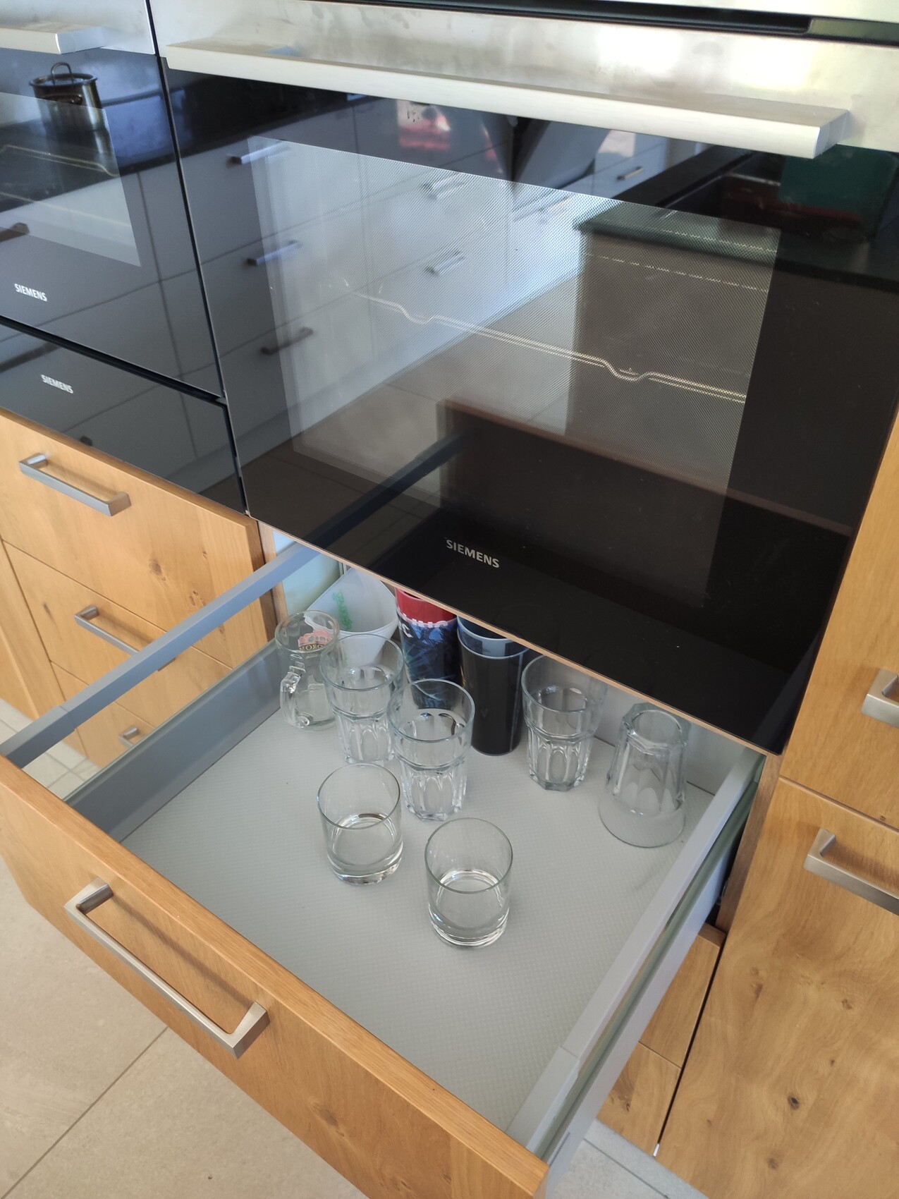Moderne Siemens Einbau-Backofenkombination; untere Auszieh-Schublade mit Gläsern.