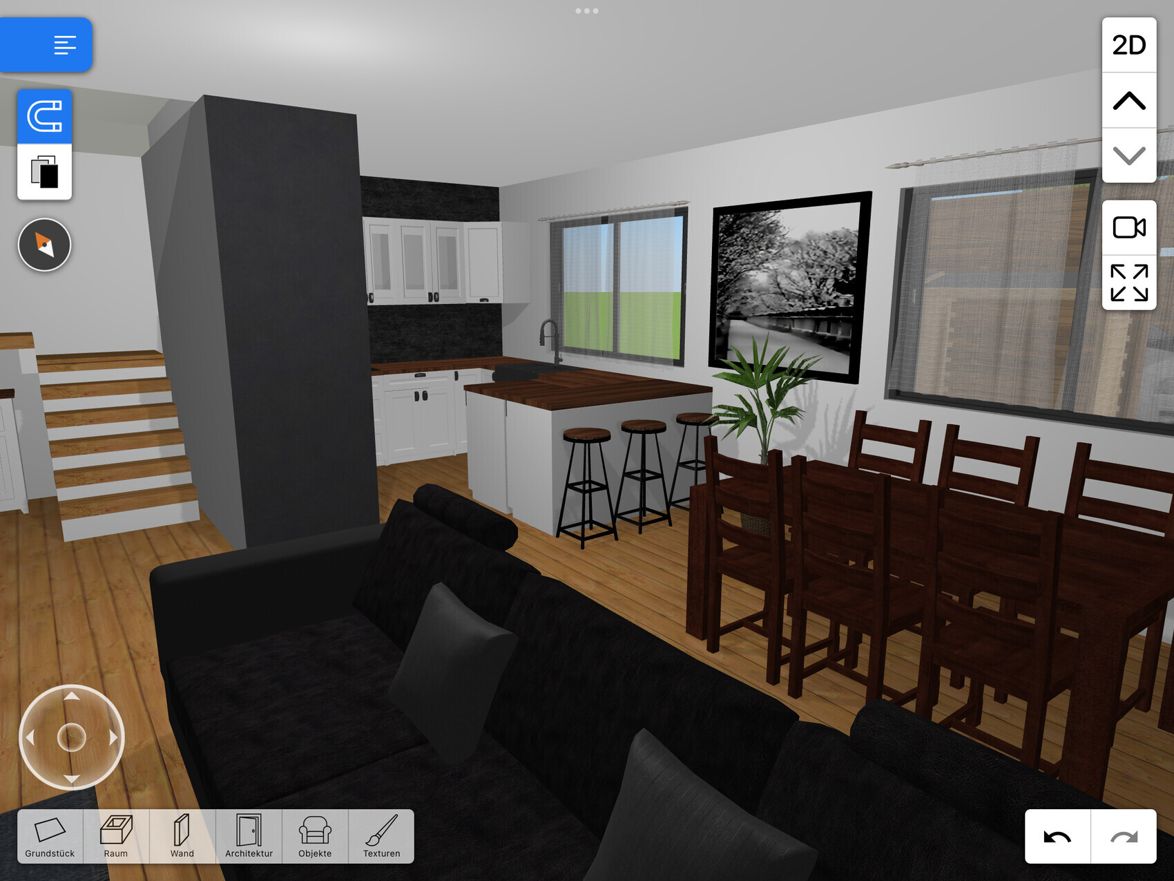 Offener Wohnbereich mit Küche, Insel, Esstisch, Treppe, großes Fenster und schwarzem Sofa.