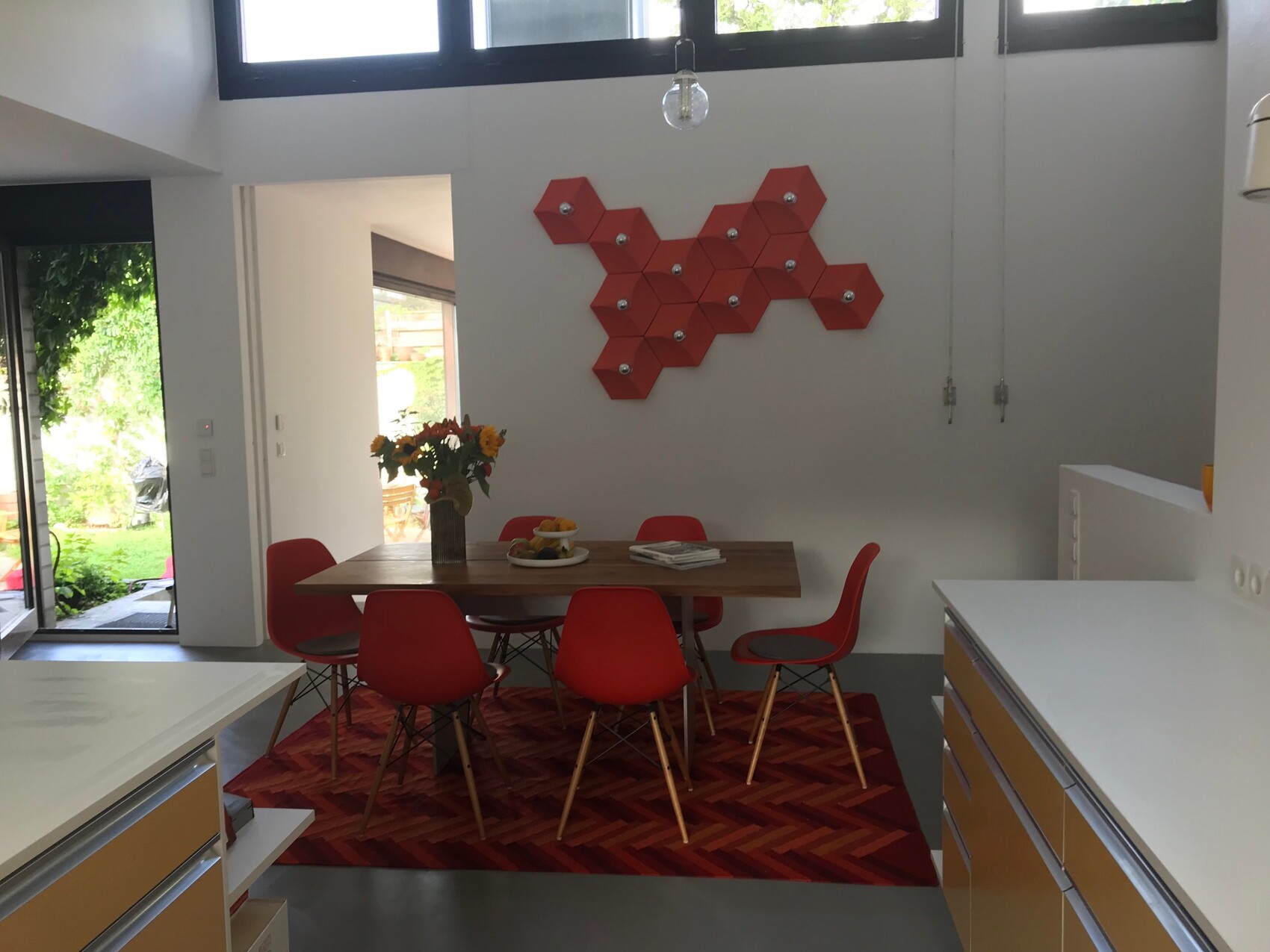 Moderne Küche mit Essbereich, roter Stuhlkreis und hexagonale Wanddeko