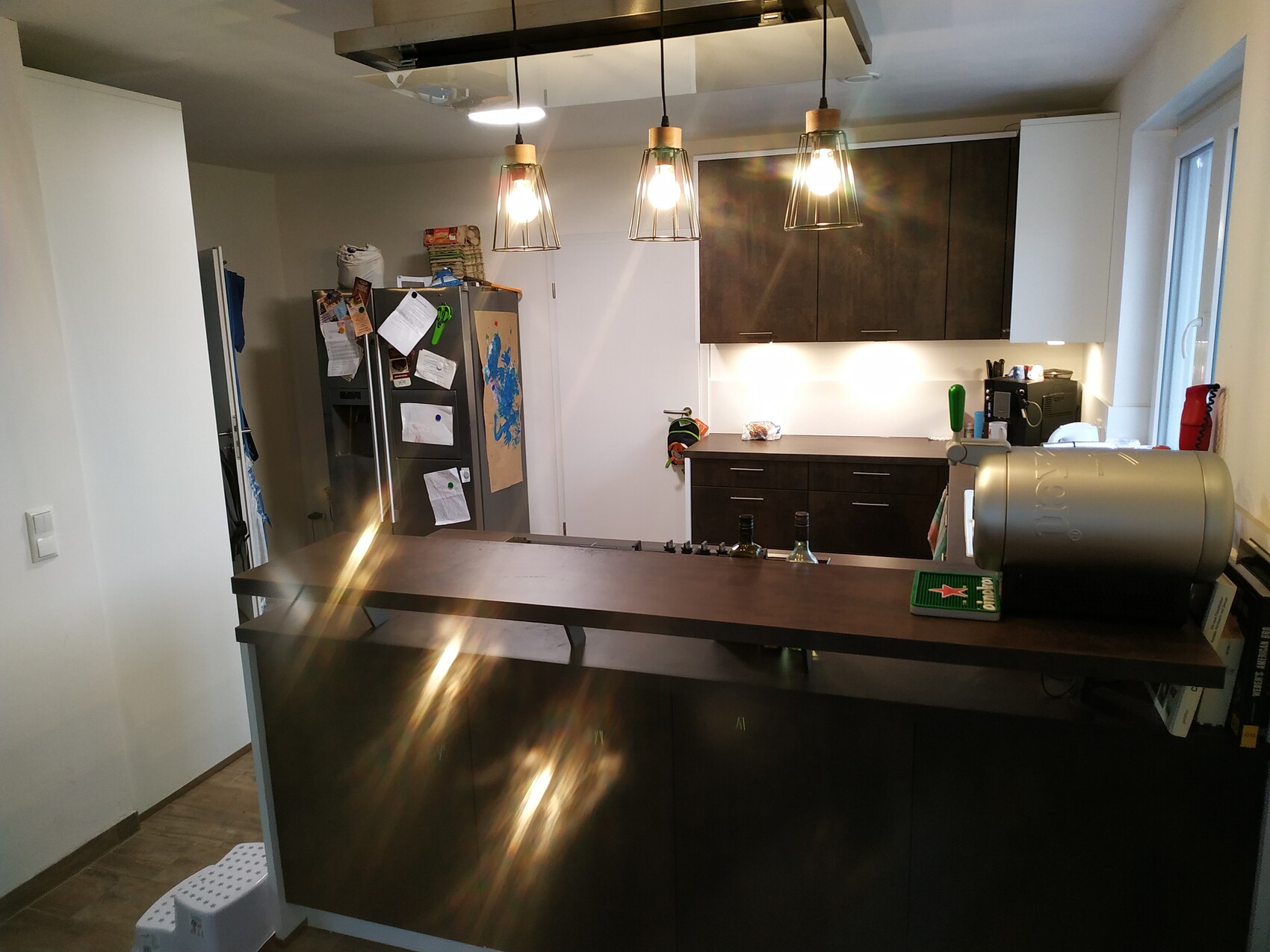Moderne Küche mit dunklen Oberschränken, Kücheninsel und Kühlschrank mit Notizen.
