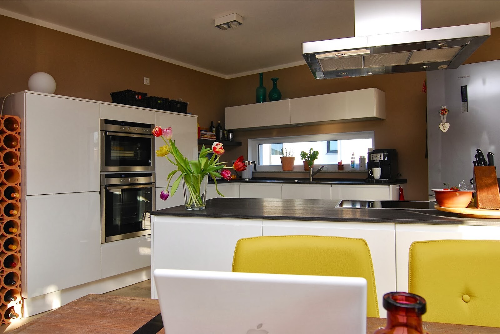 Moderne Küche mit Insel, Backöfen, Weinregal, Tulpenvase auf der Arbeitsplatte