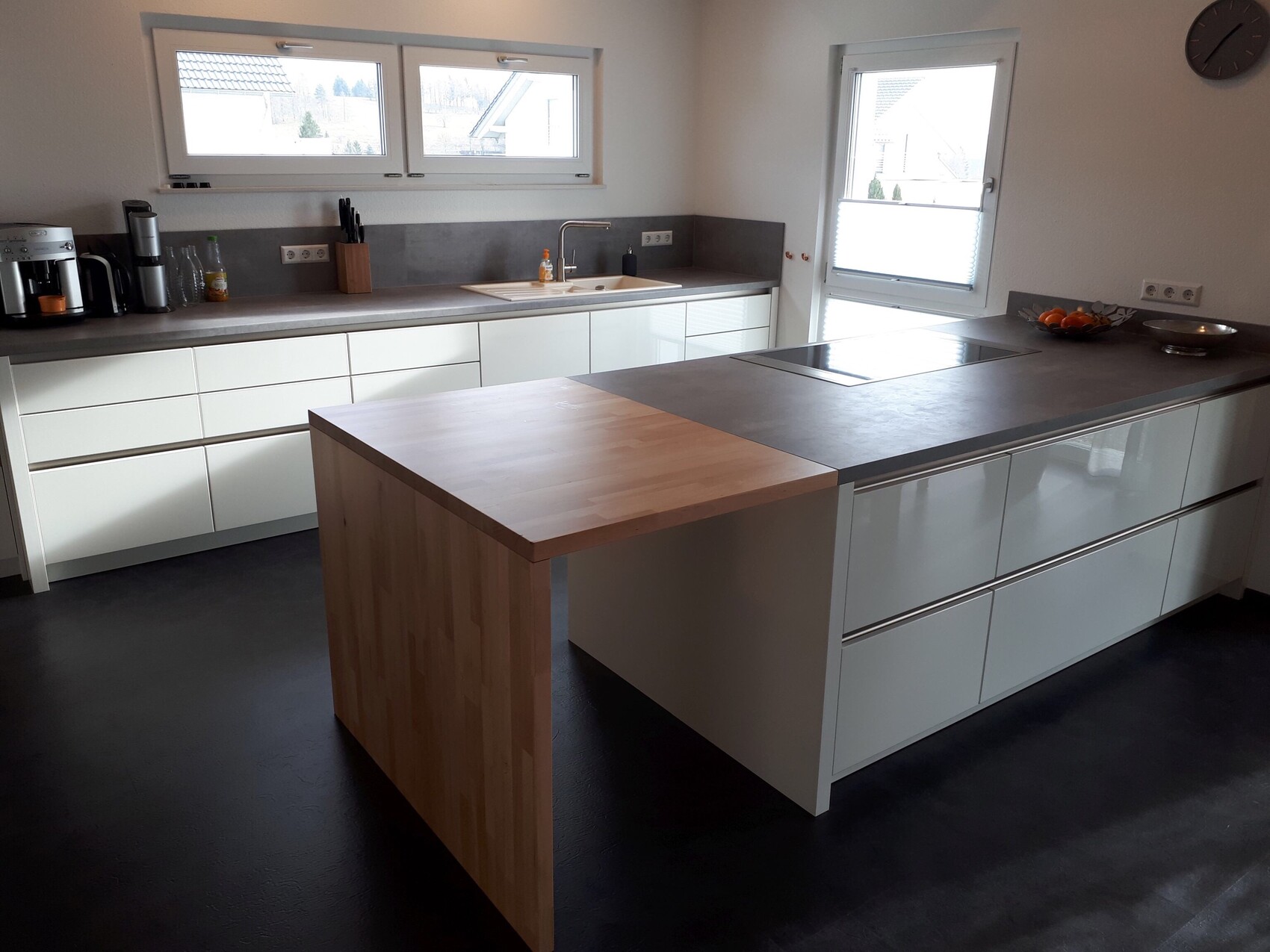 Moderne Küche mit Insel, grauen Arbeitsplatten, weißen Schränken und Spüle