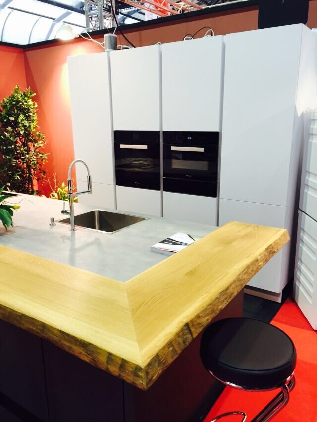 Moderne Kücheninsel mit Spülbecken, Einbau-Backofen und weißen Fronten im Küchenstudio.