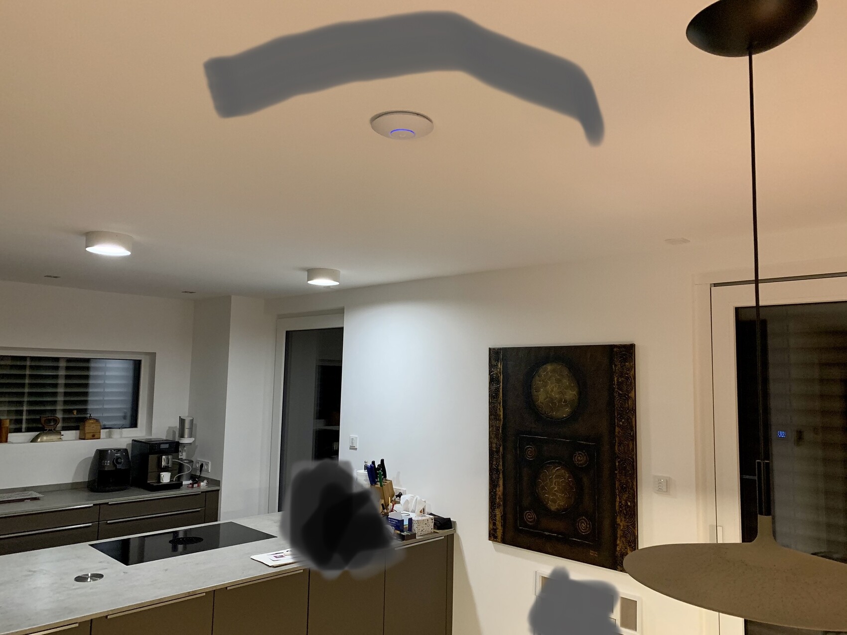 Moderne Küche mit Insel, Induktionskochfeld, Kaffeemaschine und Wandbild.