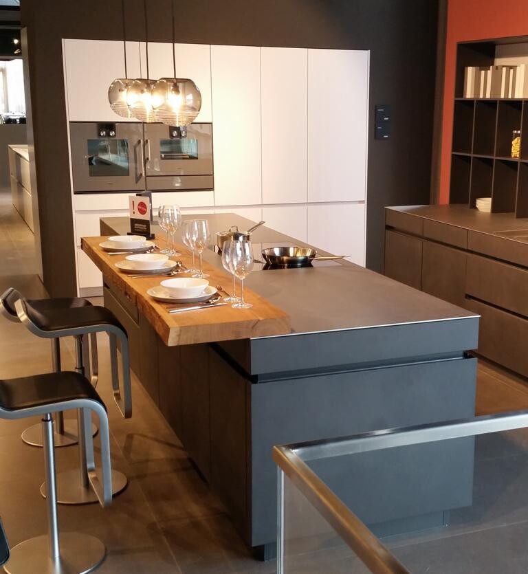 Moderne Küchenzeile mit Insel, weißen Schränken und Barhockern im Showroom.