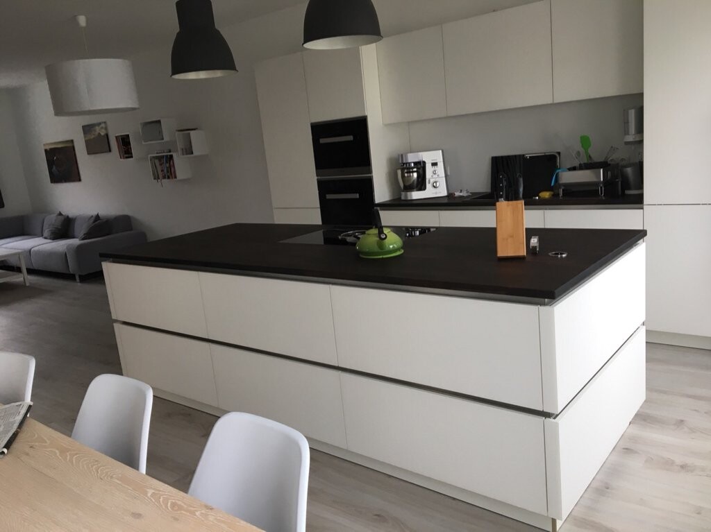 Moderne Küche mit weißer Insel, dunkler Arbeitsplatte, grünem Wasserkocher und Messerblock.