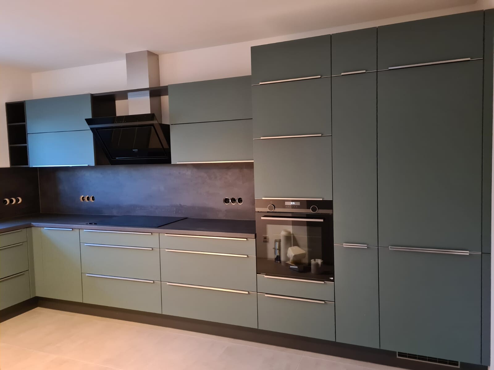 Moderne Küche mit grünen Fronten, Backofen, Dunstabzug und langen Griffleisten