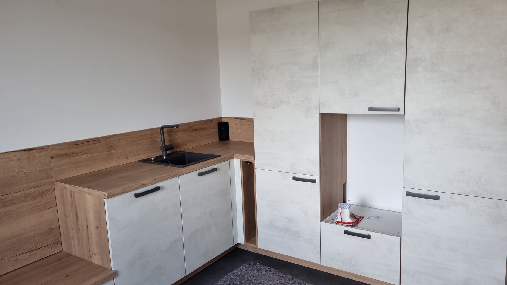 Moderne Küche mit Holz-Arbeitsplatte, grauen Fronten, schwarzer Spülarmatur und Spüle.