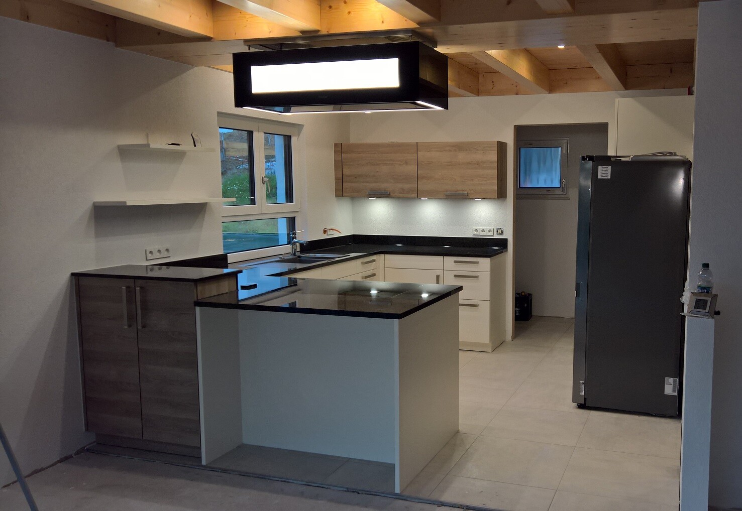 Moderne Küche mit Insel, weißen Unterschränken, Holzober- und Hängeschränken und Kühlschrank.