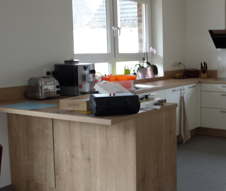 Moderne Küche mit Insel, Kaffeemaschine, Toaster und Fensterfront im Hintergrund