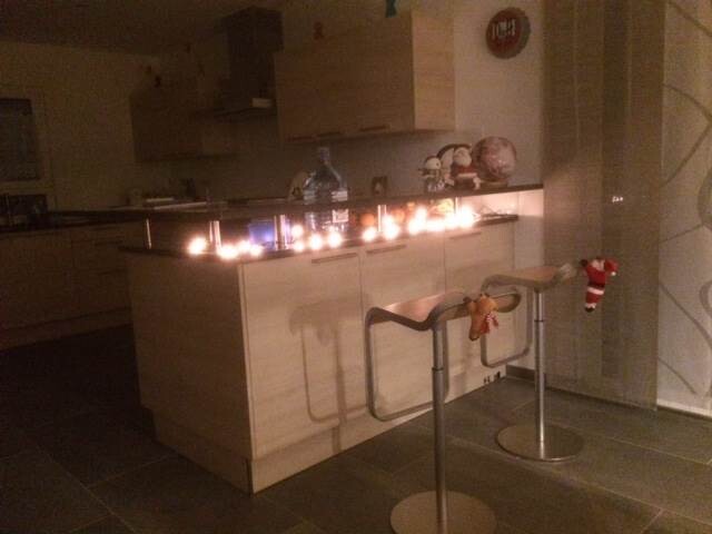Moderne Küche mit Insel, Barhockern und Weihnachtsdekoration in warmem Licht.