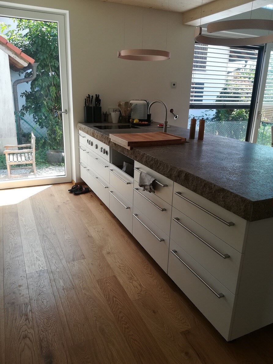 Moderne Kücheneinrichtung mit Insel, Spüle, Toaster, Messerblock; Zugang nach Außen.