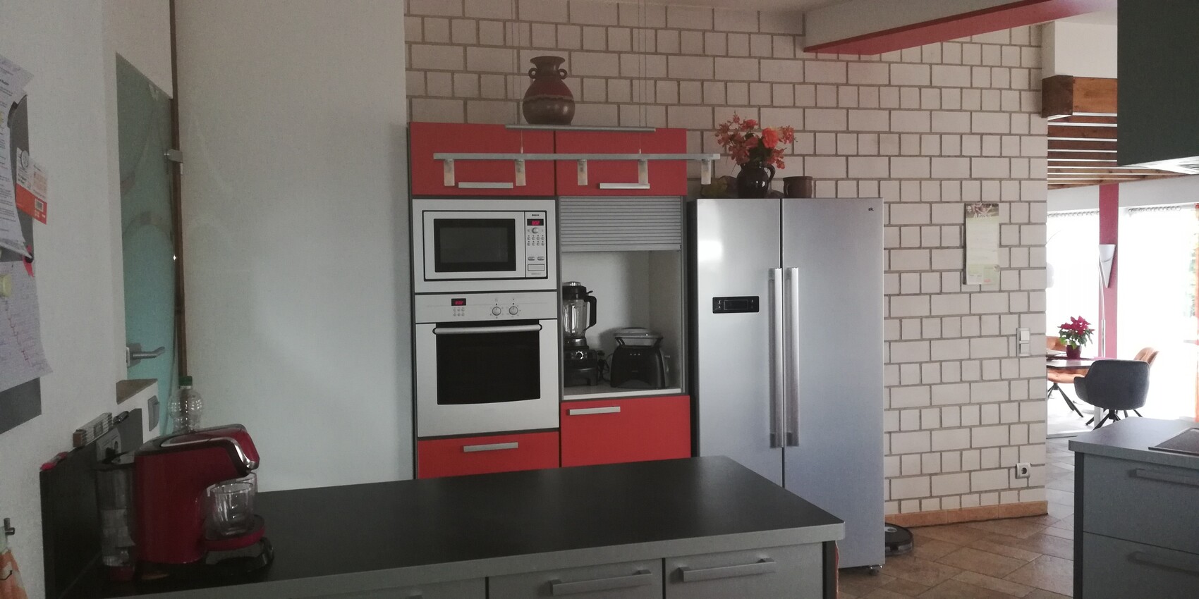 Moderne Küche mit roten Fronten, Einbauofen, Mikrowelle, Kühlschrank und Kücheninsel.