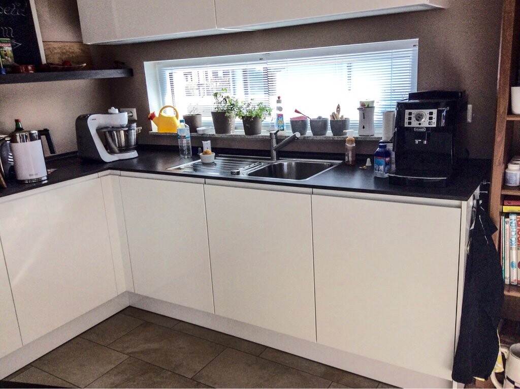 Moderne Küche mit weißen Schränken, Spüle, Kaffeemaschine und Fenster.