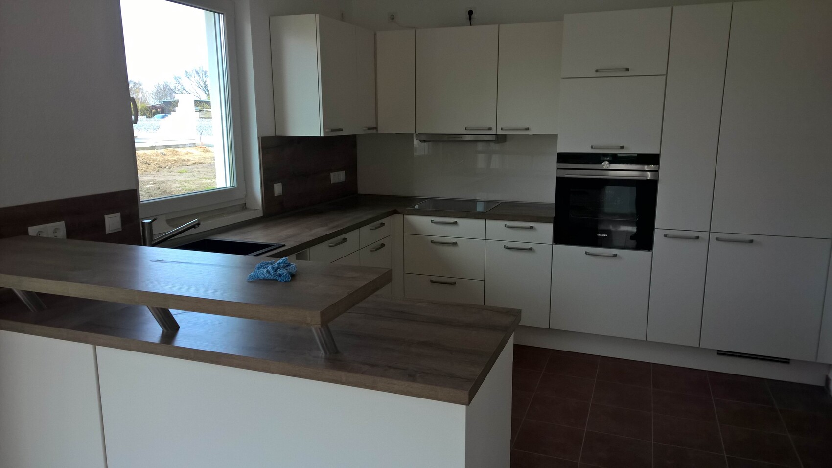 Moderne Küche mit weißen Fronten, Einbauherd und Kücheninsel