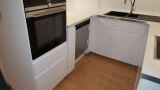 Küche mit weißen Unterschränken, Einbaubackofen und Holzboden