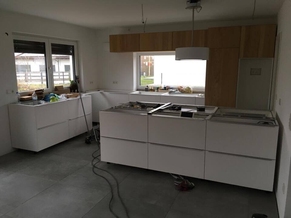 Moderne weiße Küche im Bau: Insel in Mitte, Holzoberschränke oben, Werkzeuge auf Arbeitsfläche